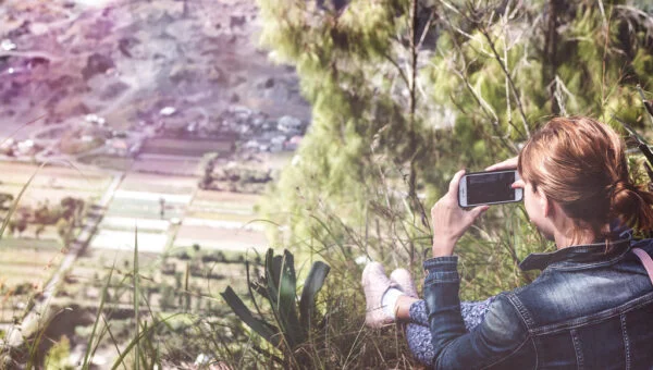Randonneuse prenant une photo avec son smartphone au sommet d'une montagne