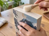 Main utilisant un pinceau souple sur la tranche supérieure d’un manga fermé