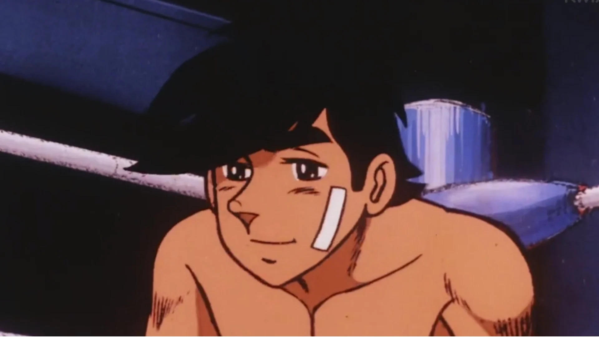 Joe Yabuki souriant, un pansement sur la joue, dans le film Ashita no Joe (1980)