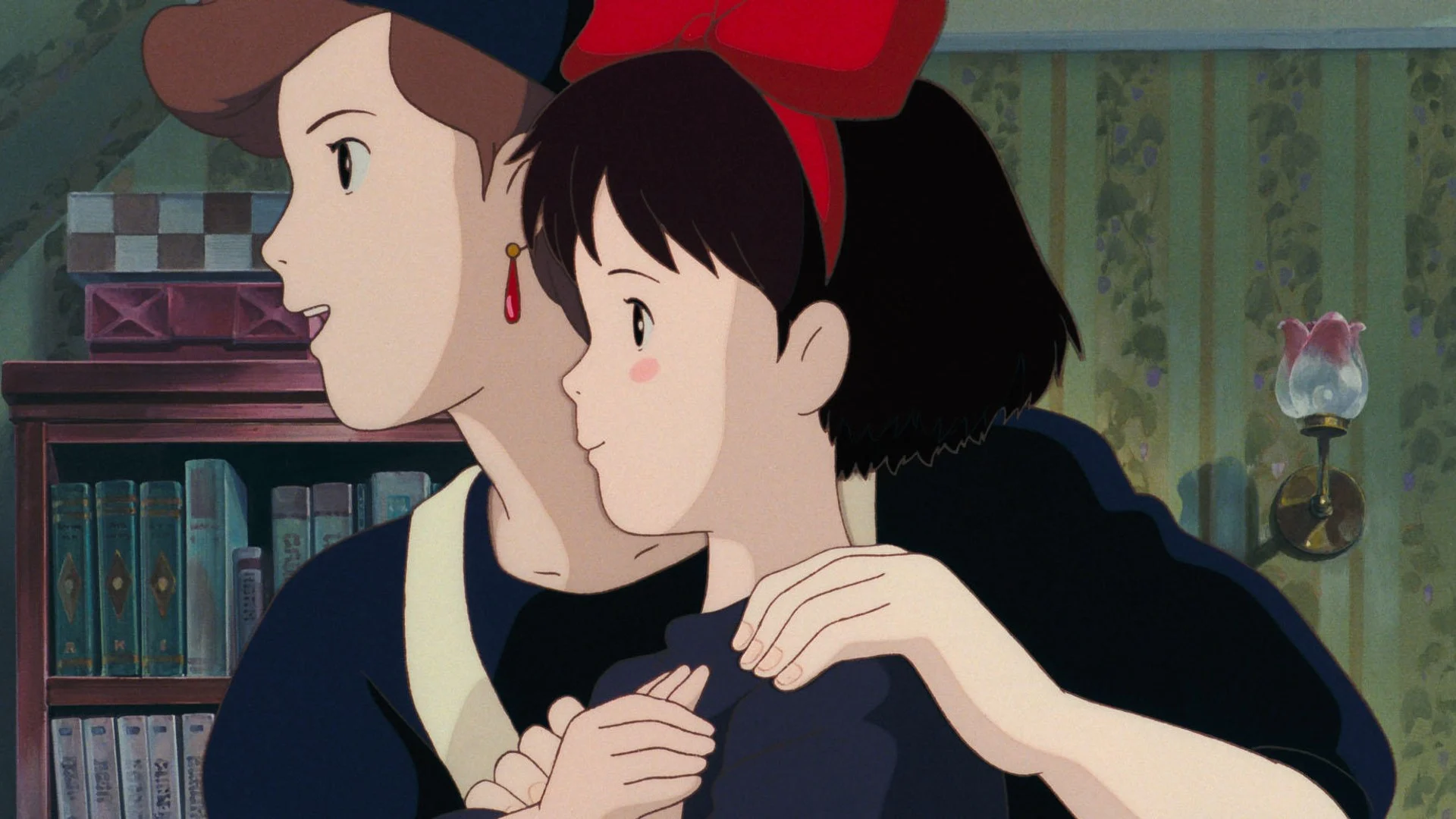 Kiki, un grand nœud rouge dans les cheveux, dans les bras de sa mère avant son départ, dans Kiki la petite sorcière