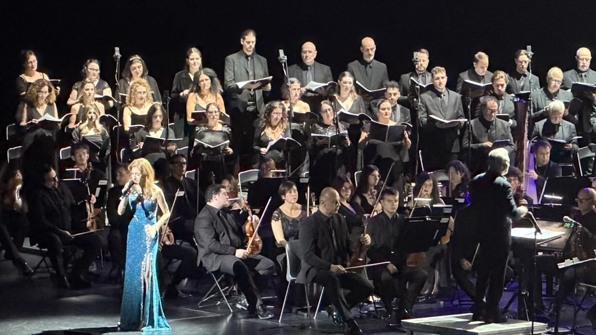 Emi Evans en robe bleue chantant devant le chœur et l'orchestre dirigés par Eric Roth