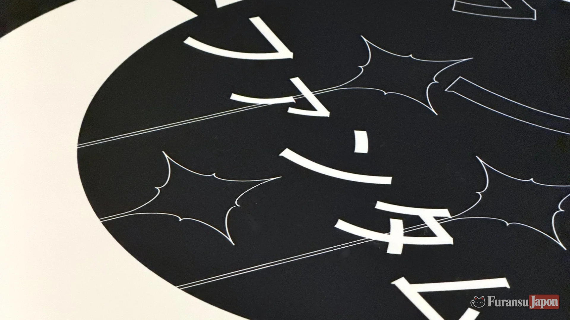 Gros plan sur le motif du Phantum Noctis : katakana ファンタム blancs, étoiles stylisées et croissant de lune sur fond noir